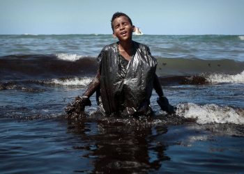 Everton Miguel dos Anjos, de 13 anos, entrou no mar para ajudar na retirada de óleo em Cabo de Santo Agostinho (Pernambuco) (Foto: Leo Malafaia/AFP)