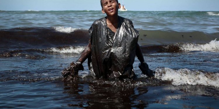 Menino coberto de óleo traduz em imagem a tragédia do litoral nordestino