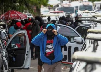 Policiais amotinados cobrem o rosto durante protesto (Foto: Jarbas Oliveira/EFE)