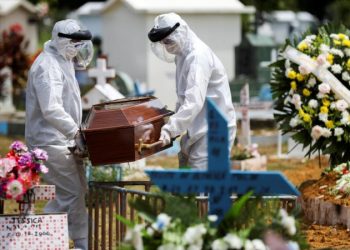 Coveiros usam roupas de proteção ao carregar caixão de idosa vítima de coronavírus (Covid-19), no cemitério Parque Taruma, em Manaus/AM (Foto: Reuters)