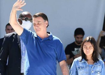 Ao lado da filha Laura, Bolsonaro, sem usar máscara de proteção, cumprimenta multidão presente (Foto: Evaiisto Sá/AFP)