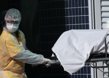 Profissional de saúde com roupa de proteção remove corpo para caminhão refrigerado em hospital do Rio de Janeiro (Foto: Ricardo Moraes)