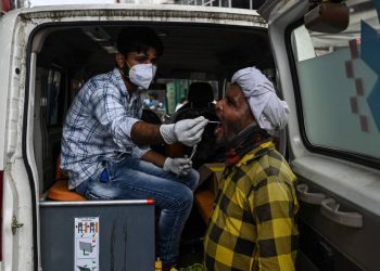 Trabalhador de saúde coleta uma amostra de um homem para teste de Covid-19 em um mercado em Gurgaon, em junho de 2021 (Foto: Money Sharma/AFP)