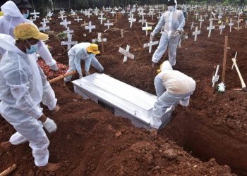 Coveiros com roupas de proteção enterram vítima da Covid em cemitério em Bekasi, na Indonésia (Foto: Rezas/AFP)