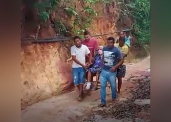 Familiares levaram Maria dos Santos, de 91 anos, sentada em uma cadeira para passar por uma estrada de terra e chegar ao hospital para ela fazer uma cirurgia (Foto: Reprodução)