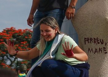 Mãe de dois filhos, Débora Rodrigues dos Santos fez questão de posar para fotos e registrar a pichação na escultura de granito, de 1961 (Foto: Reprodução)